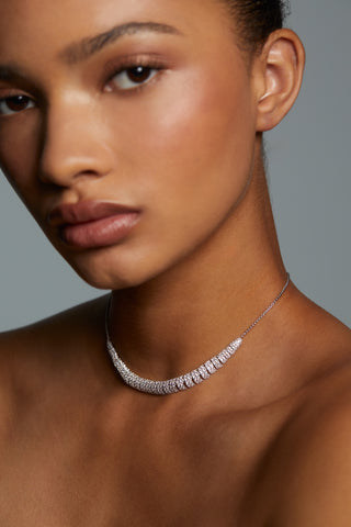 CLOSE UP IMAGE OF MODEL WEARING CRUSHED PAVE FRONTAL NECKLACE. HER HAIR IS PULLED BACK INTO A BUN AND HER FACE IS SOFTLY OUT OF FOCUS KEEPING THE NECKLACE IN CLEAR VIEW. 