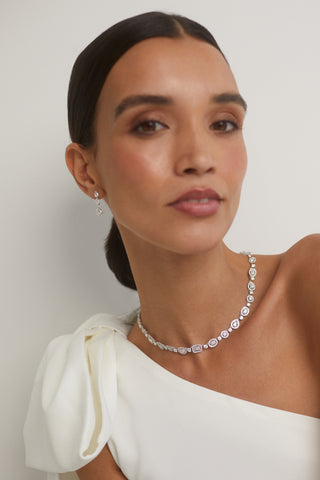 IMAGE OF A BRIDE WEARING OUR RADIANT FULL COLLAR CZ NECKLACE WITH MATCHING DROP EARRINGS.  HER WHITE DRESS IS OFF THE SHOULDER WITH A BOW DETAIL AND HER HAIR IS PULLED BACK SLEEKLY. 